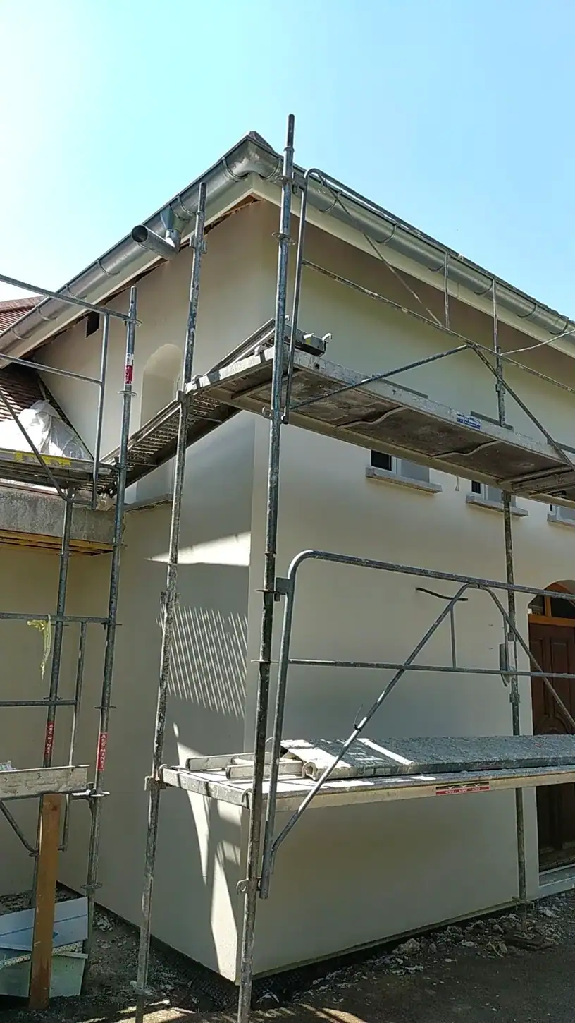 Façade de maison mise en teinte claire, avec échafaudage encore en place