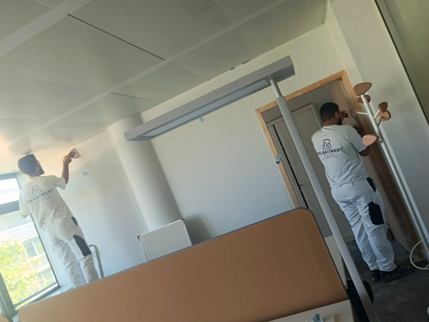 Un peintre BN BÂTIMENT travaille sur les finitions d'un espace de bureaux